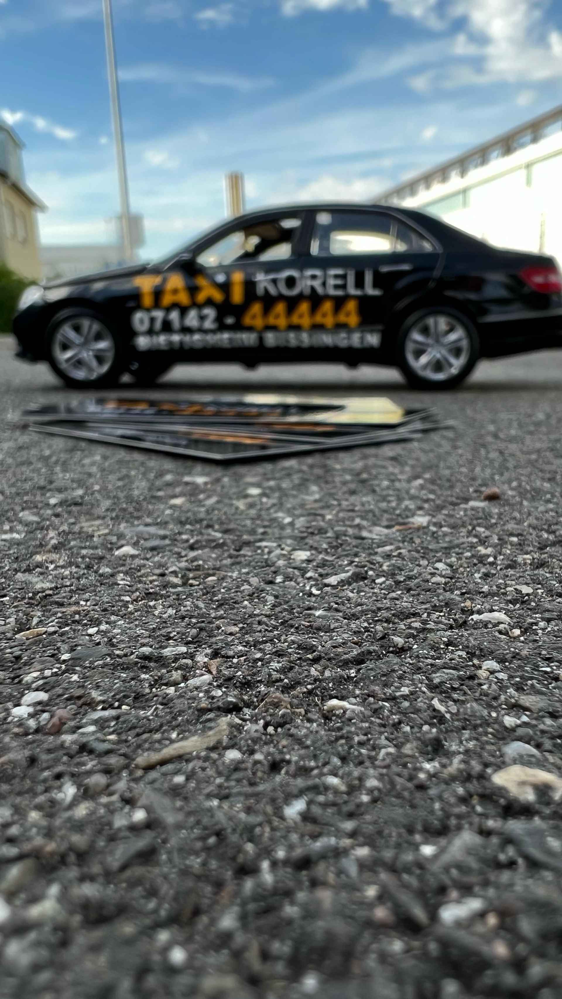 Bild mit Visitenkarten und einem Auto von Taxi Korell im Hintergrund