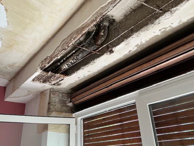 Beschädigter Fenstersturz mit freiliegender Bausubstanz und Feuchtigkeitsschäden vor der Wasserschadensanierung.