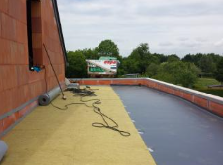 Terrasse sur le toit avec des surfaces jaunes et bleues, des câbles et un mur de briques