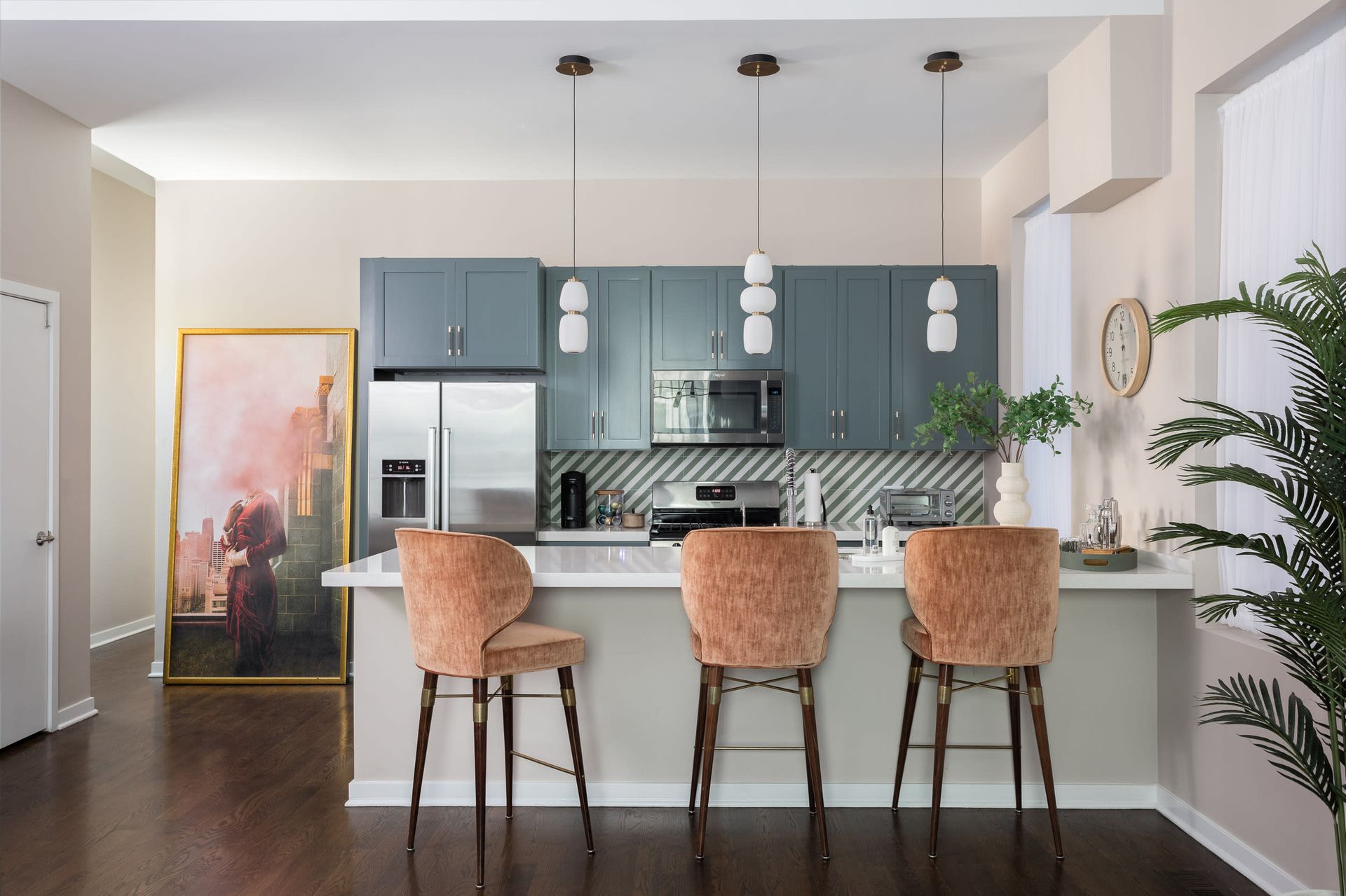 Modern kitchen with blue cabinets, island seating, pendant lights, and dark wood floors