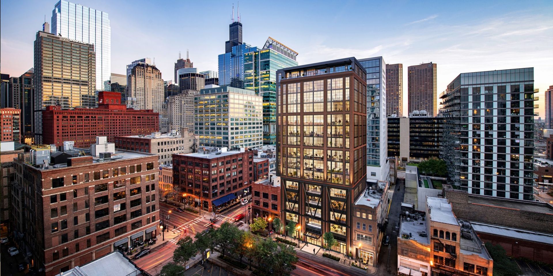 Downtown city skyline at dusk with illuminated high-rise buildings and streets below