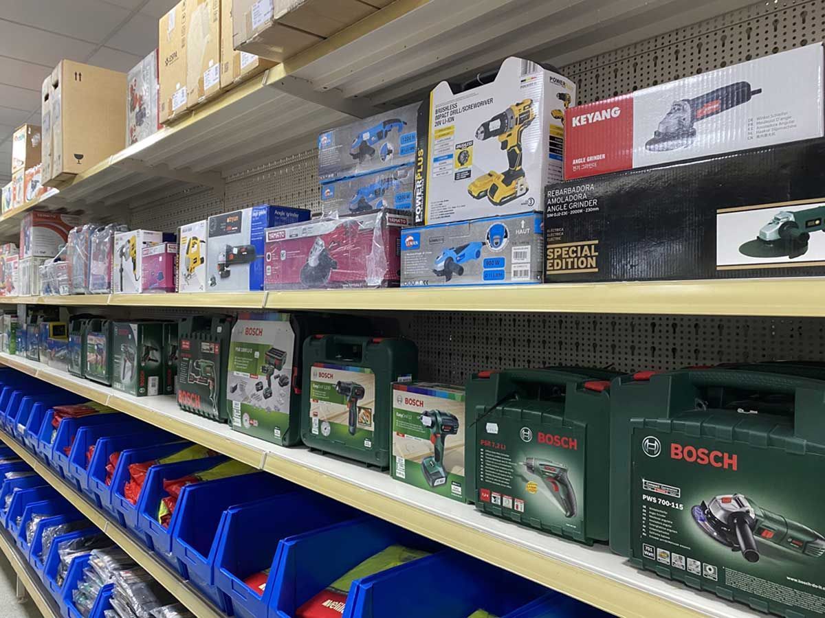 Estanterías de una ferretería que exhiben diversas herramientas eléctricas, incluyendo maletines Bosch y taladros y amoladoras en cajas.