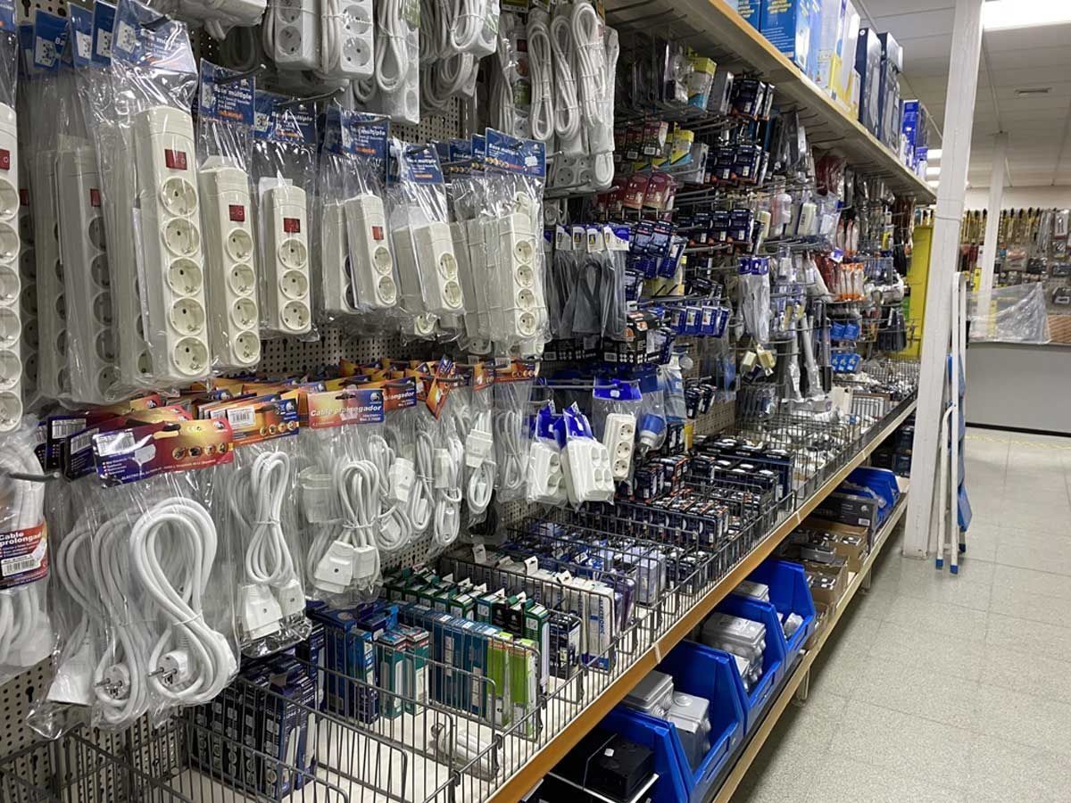 Un pasillo de una tienda repleto de regletas eléctricas, alargadores y accesorios de ferretería empaquetados de diversos tipos.