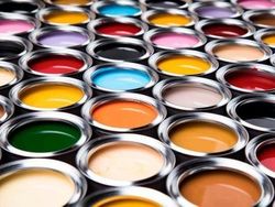 Primer plano de numerosas latas metálicas abiertas, llenas de pinturas de colores vivos, dispuestas en forma de cuadrícula.