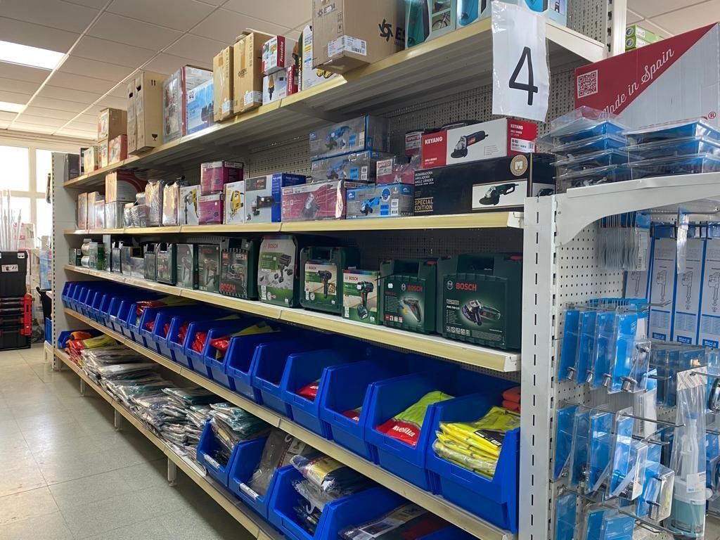 Los estantes de la tienda están repletos de diversas herramientas eléctricas, cajas de equipos y contenedores organizadores de plástico azul.