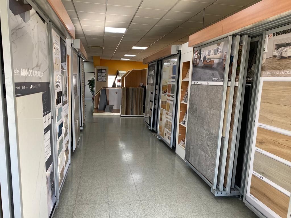 Un pasillo de la sala de exposición revestido con múltiples estantes verticales que muestran diversas muestras de azulejos y suelos a ambos lados.