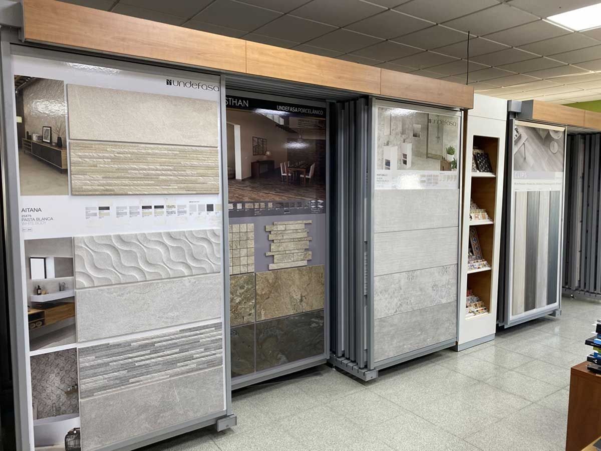 Un escaparate con varios estantes deslizantes que muestran diversos azulejos de pared en tonos neutros de gris, beige y blanco.