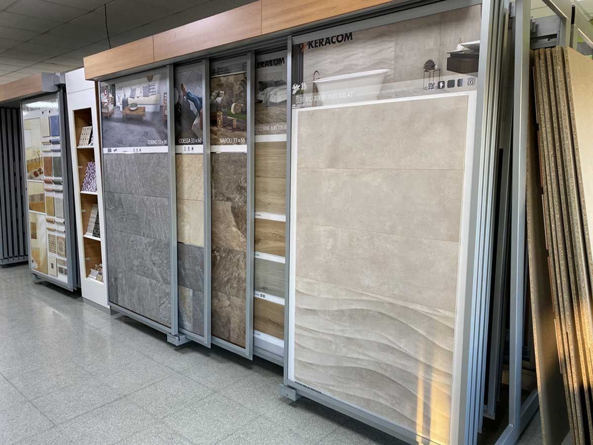 Un expositor de sala de exposición que contiene varios paneles verticales de gran tamaño con diferentes diseños de azulejos y texturas de piedra.