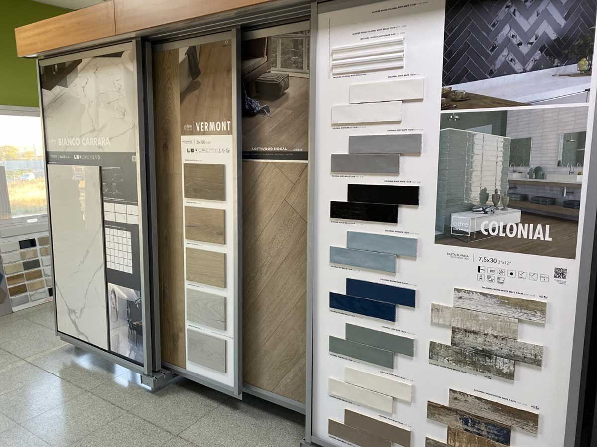 Un escaparate con varios paneles deslizantes que muestran diversas muestras de azulejos, incluyendo mármol, imitación madera y ladrillo.