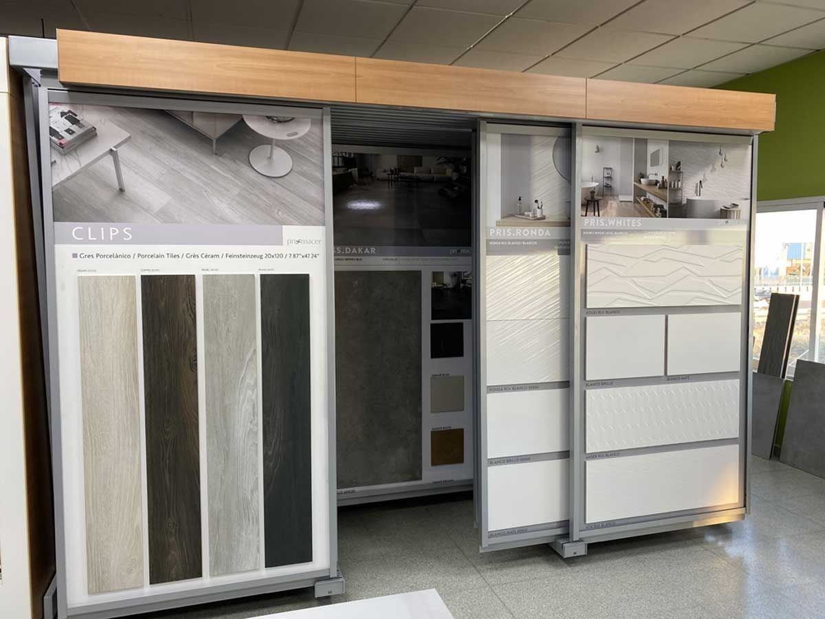 Un expositor de muestra que exhibe diversas muestras de pisos de baldosas blancas y con apariencia de madera en paneles deslizantes.