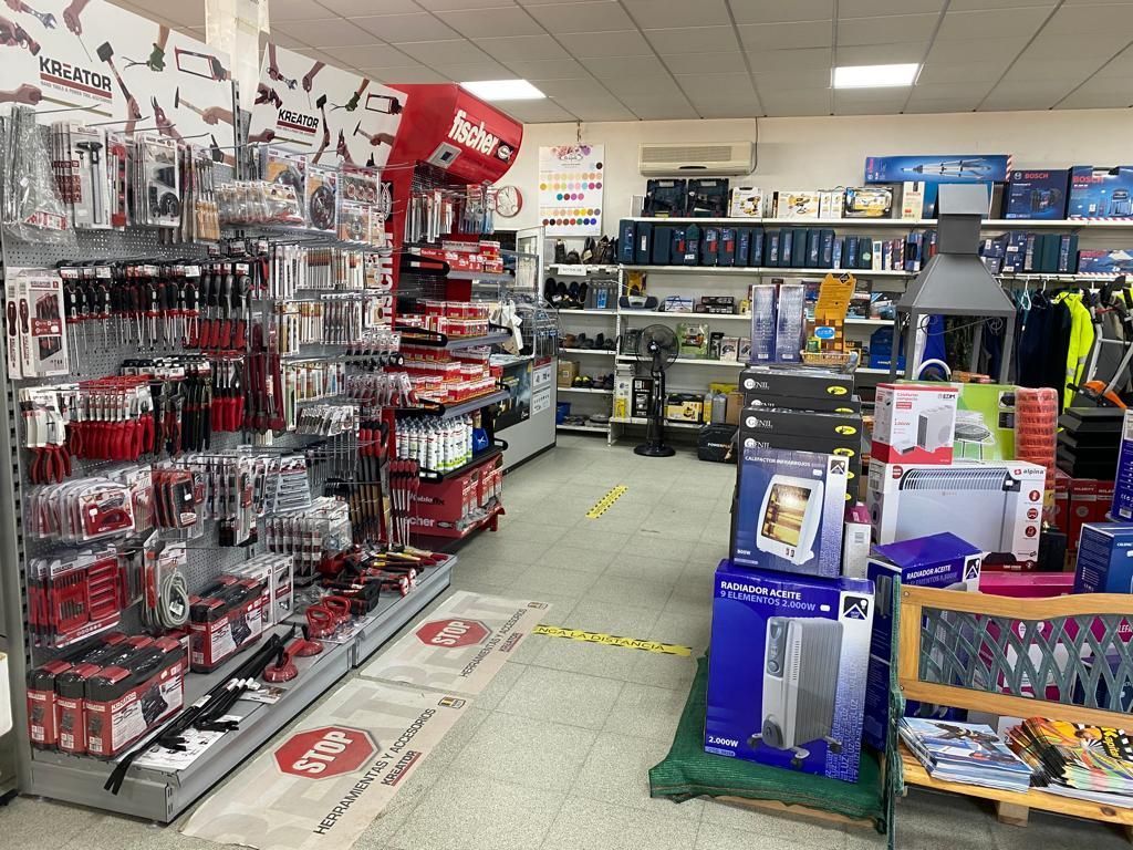 Vista interior de una ferretería o tienda de mejoras para el hogar con estantes repletos de herramientas, electrodomésticos y suministros.