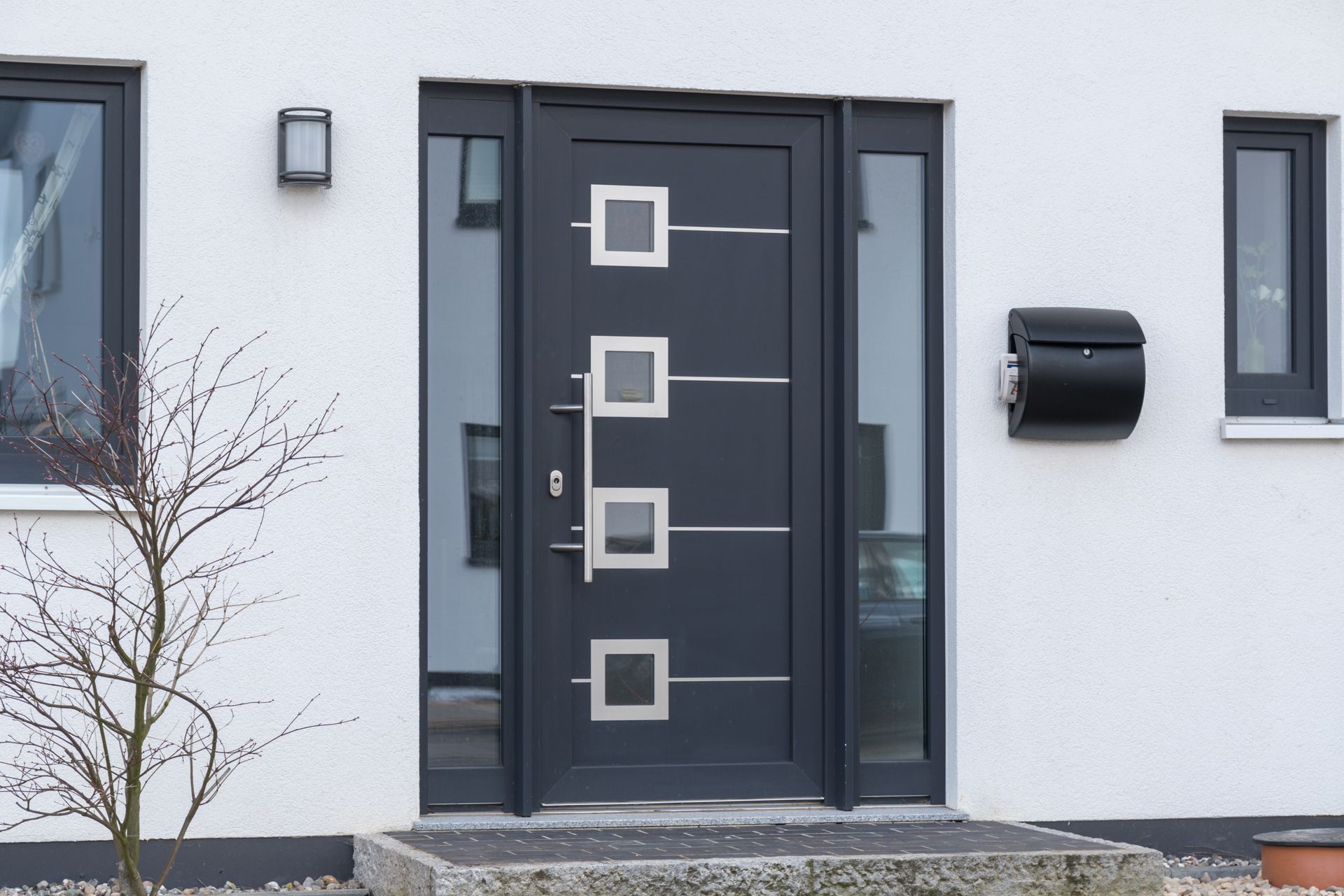 Porte d'entrée moderne avec fenêtres carrées sur une façade de maison blanche