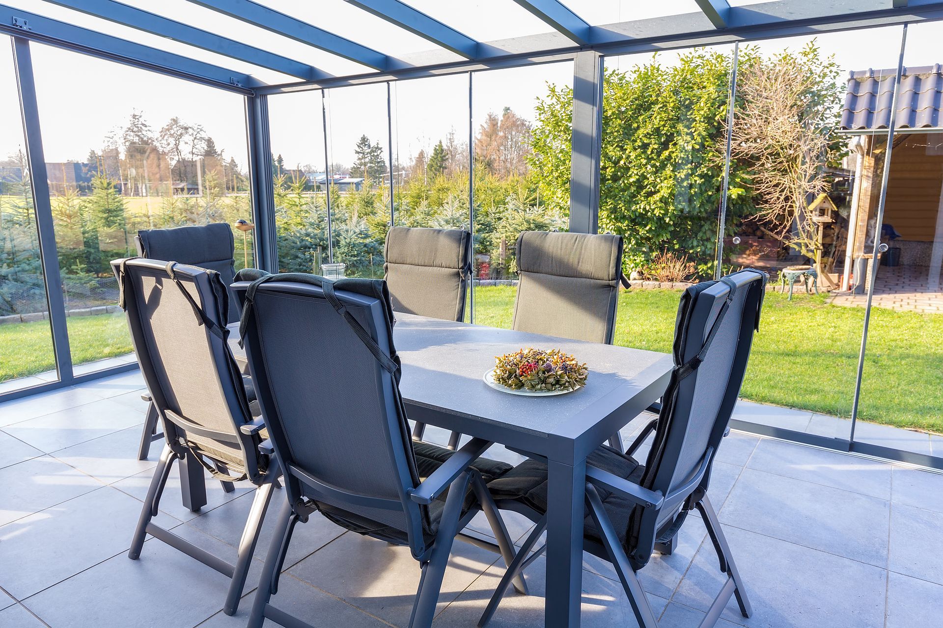 Terrasse couverte avec coin repas, table, quatre chaises et vue sur le jardin