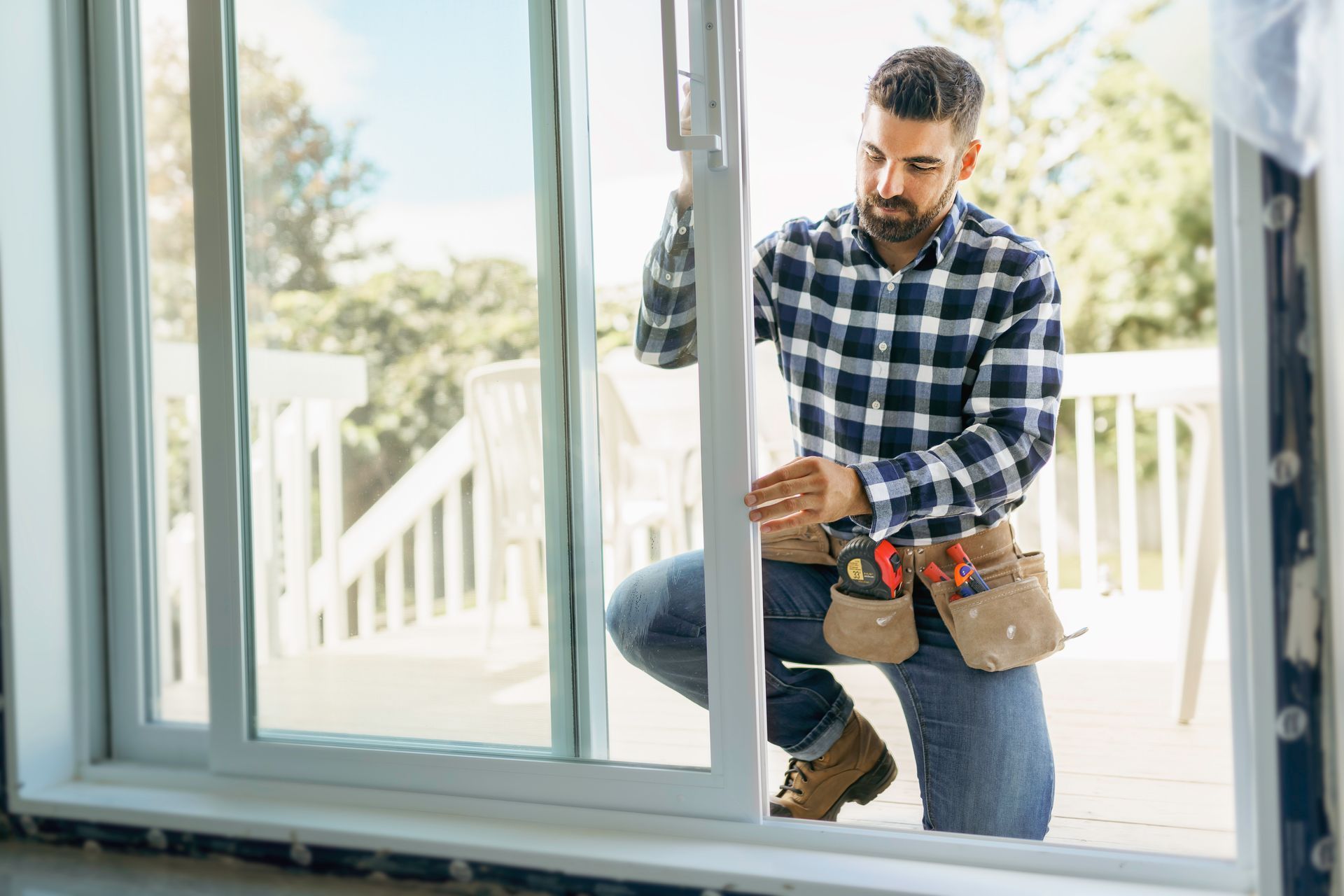 Un homme installe une vitre avec une ceinture à outils dans l'intérieur lumineux d'une maison.