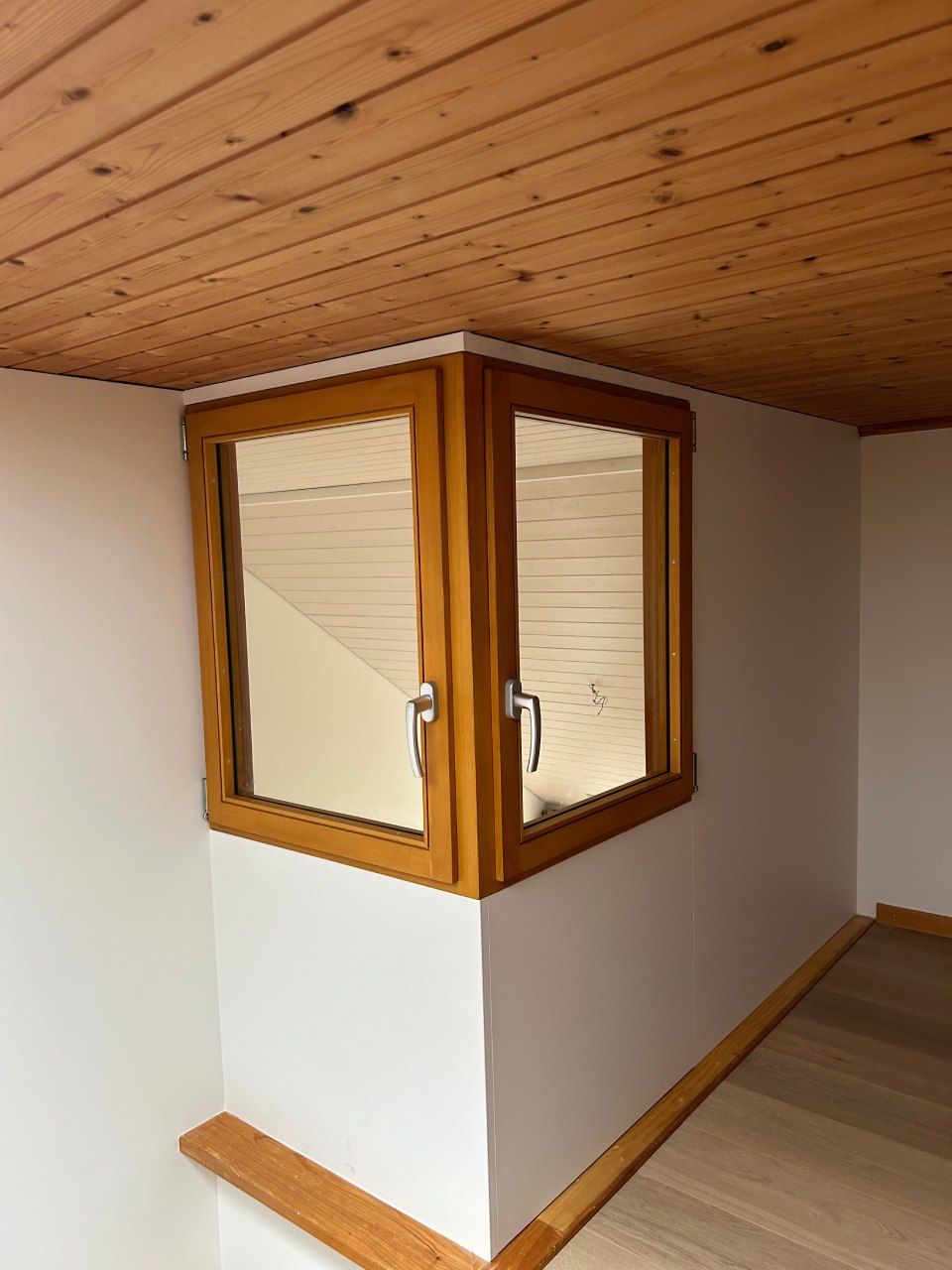 Un coin d'une pièce avec une fenêtre et un plafond en bois