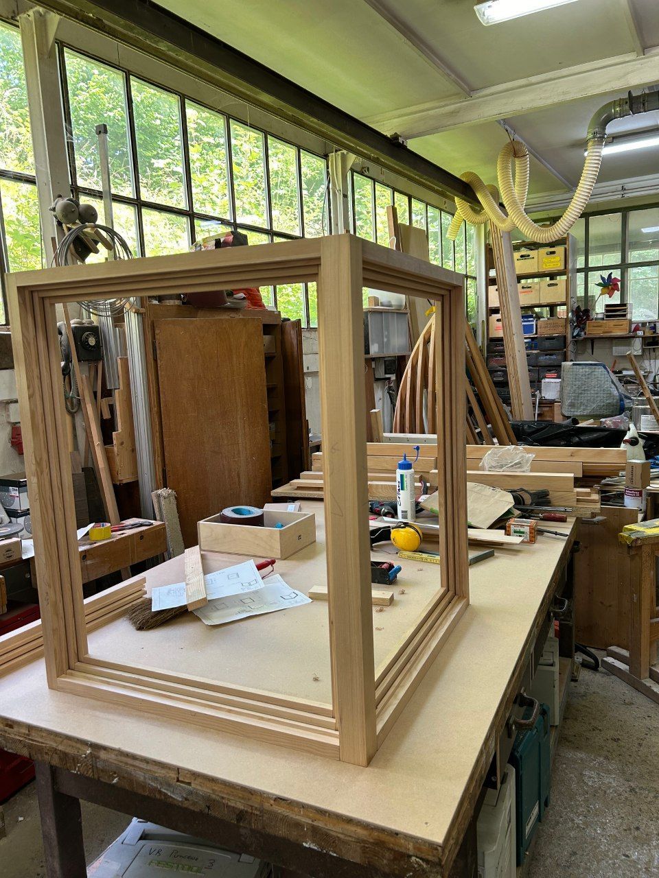 Un cadre en bois est posé sur une table en bois dans un atelier.