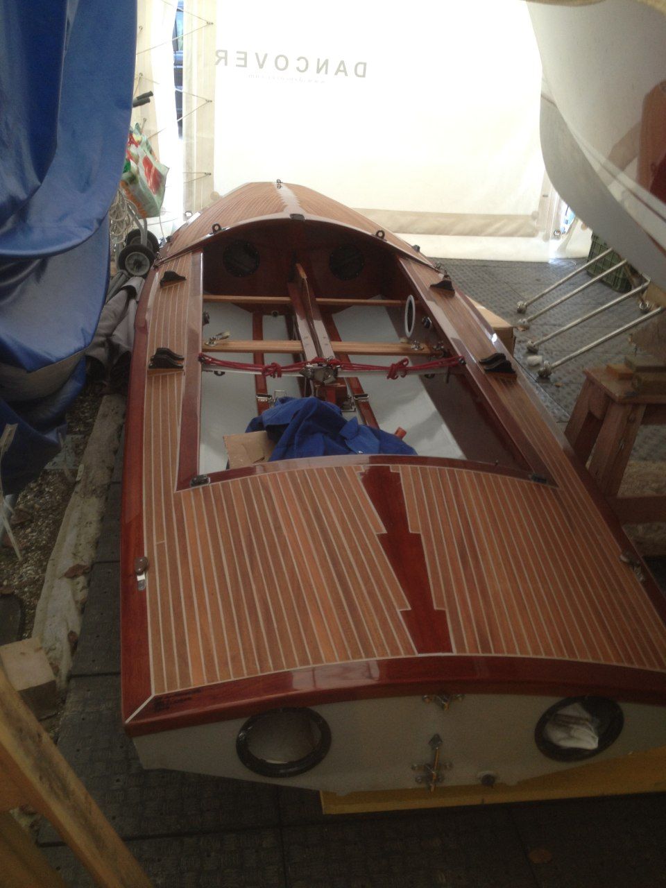 Un petit bateau avec une terrasse en bois se trouve dans un garage
