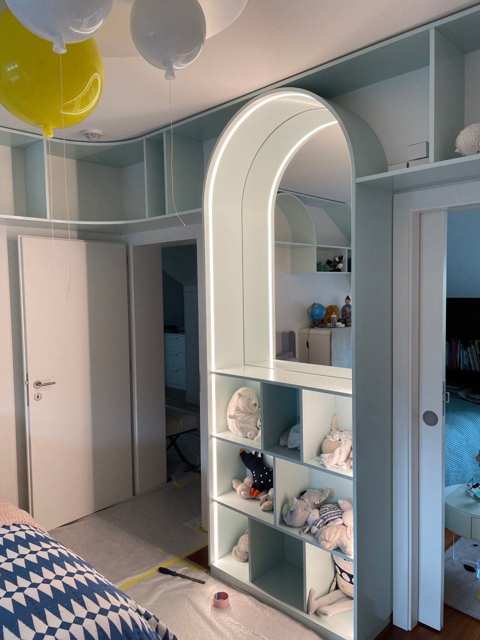 Une chambre avec un lit et une étagère avec des ballons suspendus au plafond.