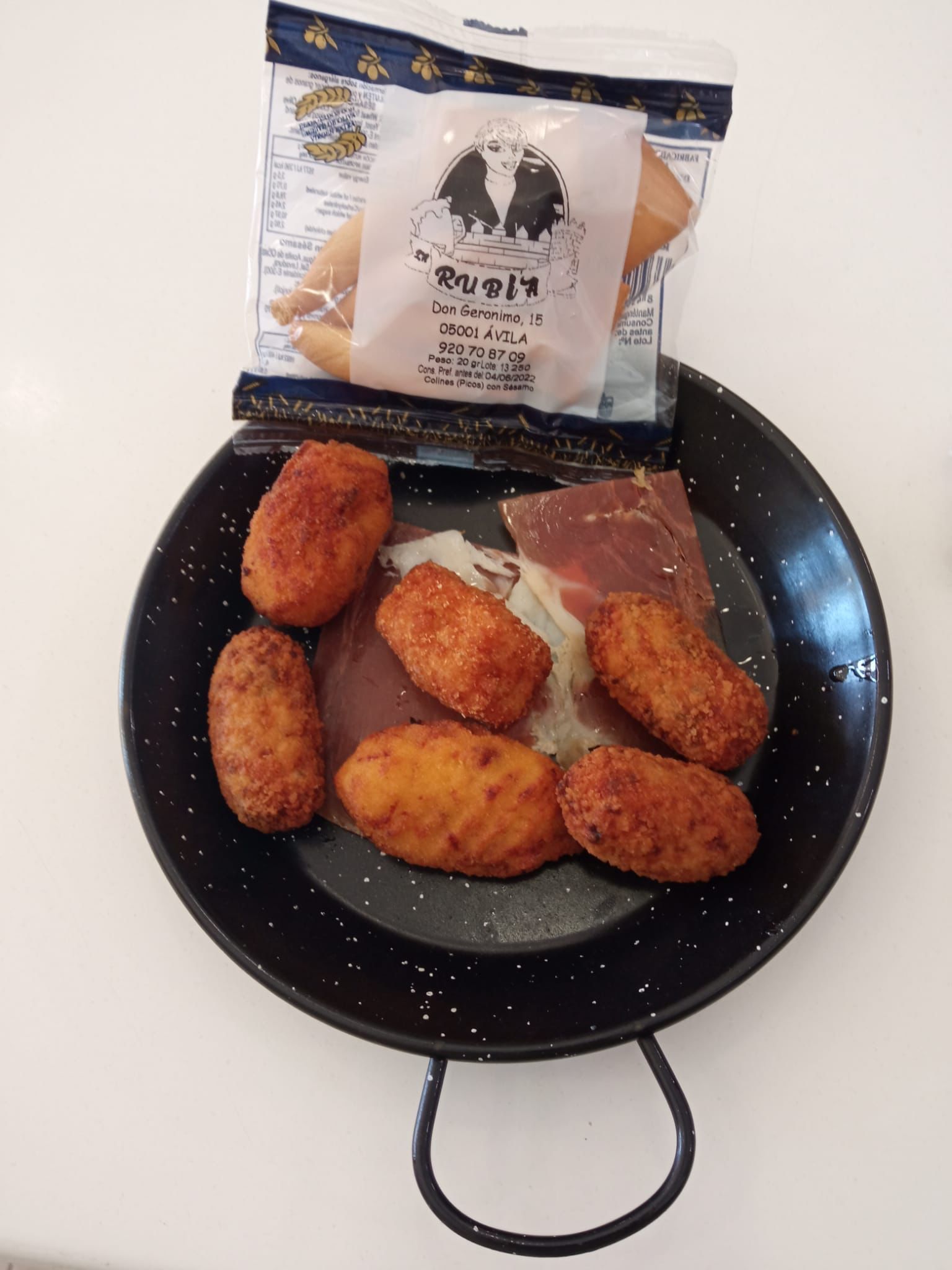 Una sartén negra llena de comida frita junto a una bolsa de comida.