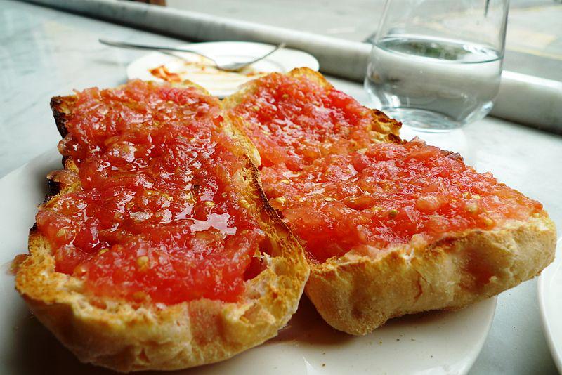 Dos rebanadas de pan cubiertas con salsa de tomate en un plato blanco.