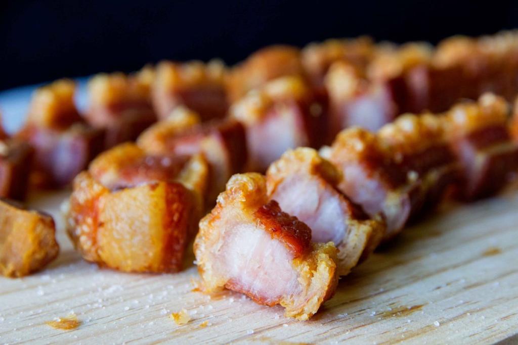 Un primer plano de carne frita en una tabla de cortar de madera.
