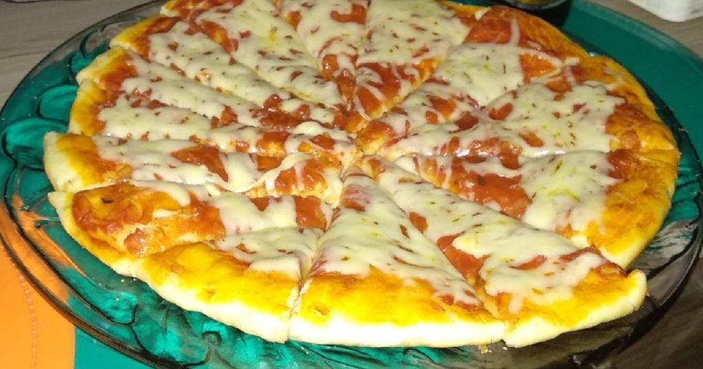 Una pizza con pepperoni y queso en un plato de vidrio.