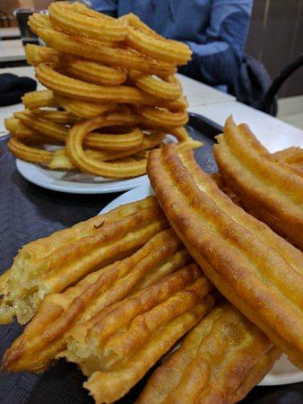 Una pila de churros está sobre una mesa al lado de un plato de churros.