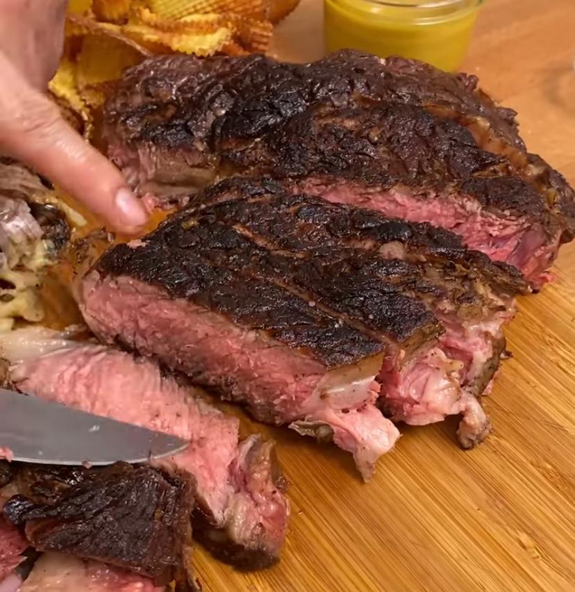 Una persona está cortando un filete en una tabla de cortar de madera.