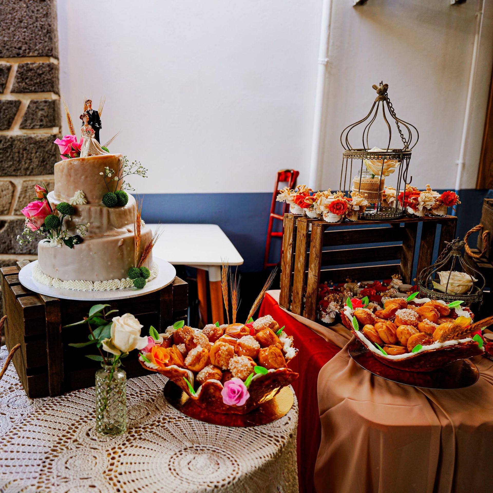 Table de desserts décorée avec un gâteau à étages, des pâtisseries et des compositions florales lors d’une fête en intérieur
