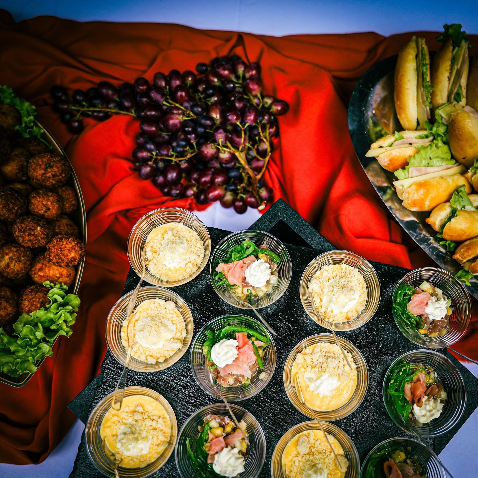 Buffet avec des raisins, des amuse-bouches frits, des chips de plantain et de petits pots de dessert crémeux