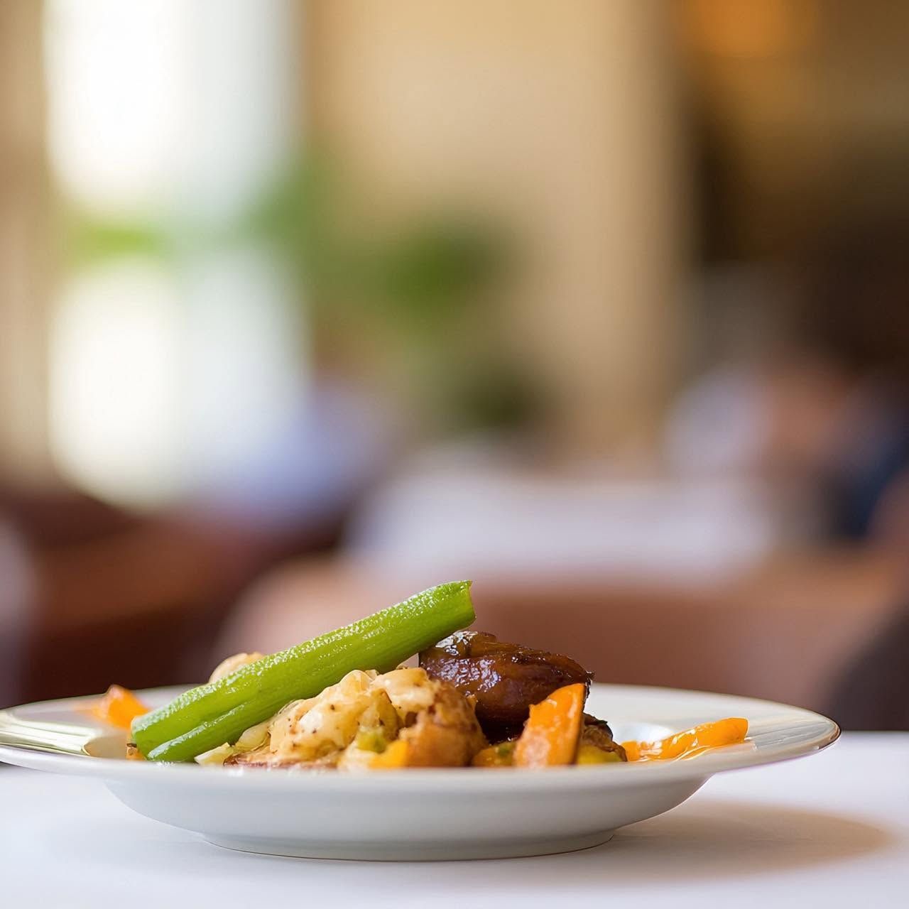 Plat gastronomique dressé avec des asperges et des légumes dans une assiette blanche, dans un restaurant