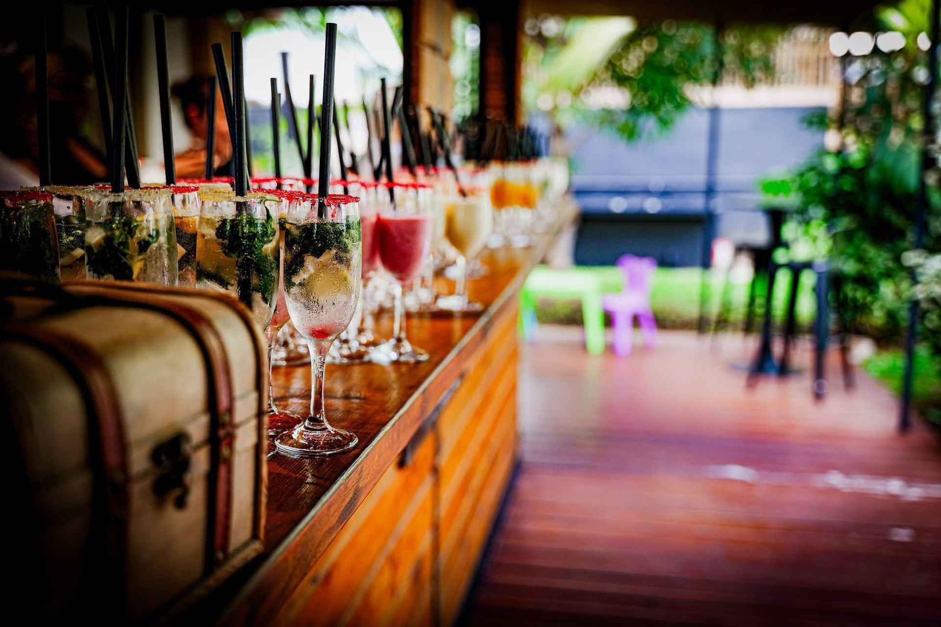 Rangée de cocktails colorés sur un comptoir en bois dans un salon à ciel ouvert