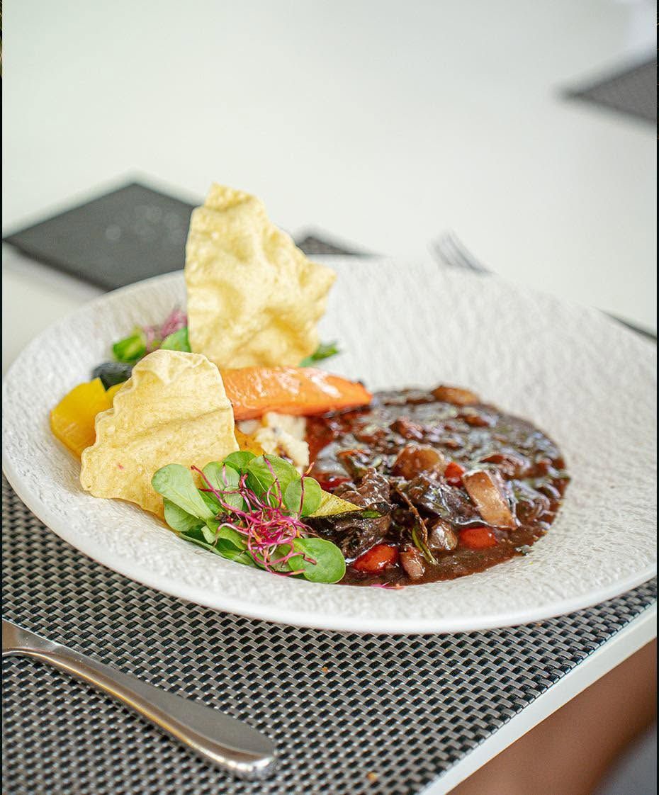 Repas gastronomique dressé, accompagné d’une sauce foncée, de légumes et de chips croustillantes