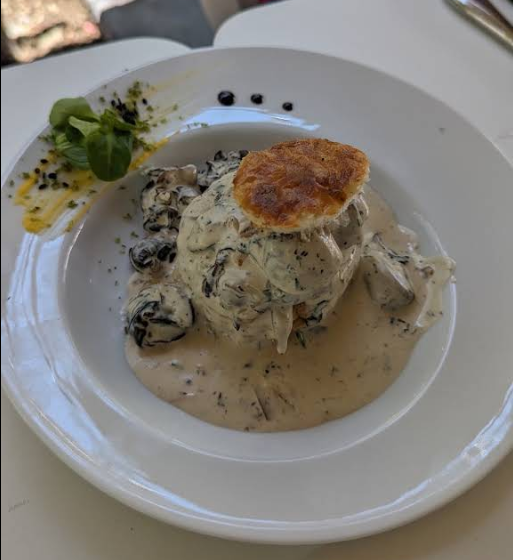 Plat crémeux aux champignons, recouvert d’une pâte feuilletée dorée, servi dans une assiette blanche et garni d’herbes.