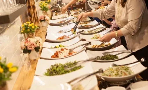Des invités se servent à un long buffet garni de plats et de fleurs