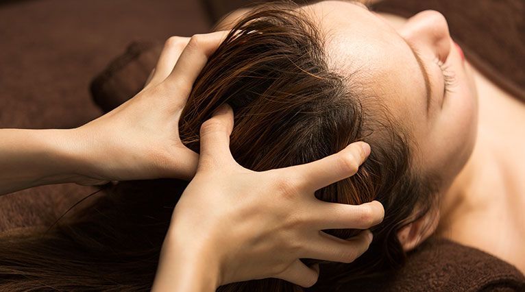Une femme en train de se faire masser la tête.