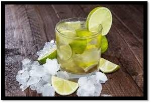 Un refrescante cóctel de caipirinha con rodajas de lima y hielo sobre una superficie de madera.