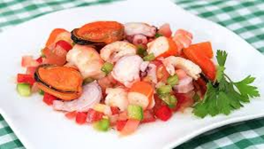 Ensalada de mariscos con mejillones, camarones y pulpo, servida en un plato blanco con verduras picadas.