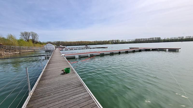 Ein Holzsteg, der zu einem großen Gewässer führt.