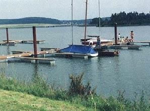 Eine Gruppe Boote liegt an einem Steg an einem See.