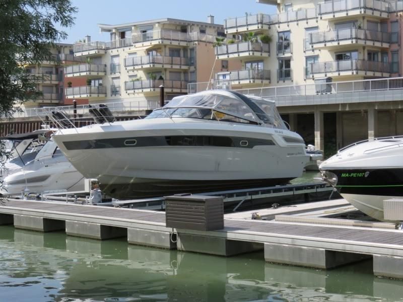 Ein Boot liegt in einem Yachthafen vor einem Gebäude im Hintergrund