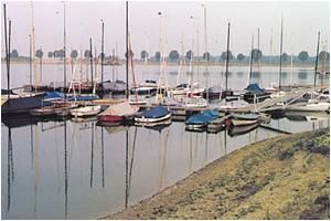 In einem Yachthafen an einem See liegen mehrere Boote vor Anker.