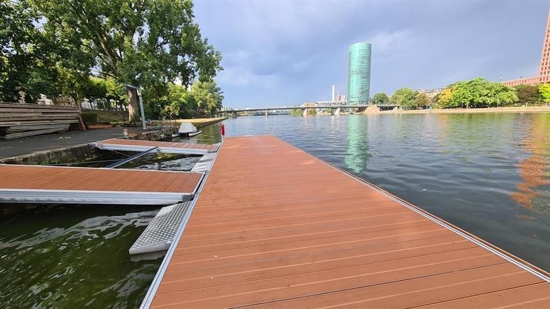 Ein Holzsteg liegt neben einem Gewässer.