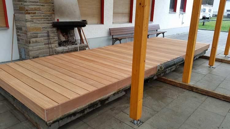 Eine Holzterrasse mit einem Kamin im Hintergrund