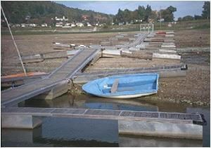 Ein kleines blaues Boot liegt an einem Dock.