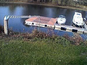 Zwei Boote liegen an einem Steg an einem See.