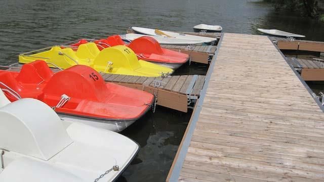 An einem Dock liegt eine Reihe Tretboote vor Anker.