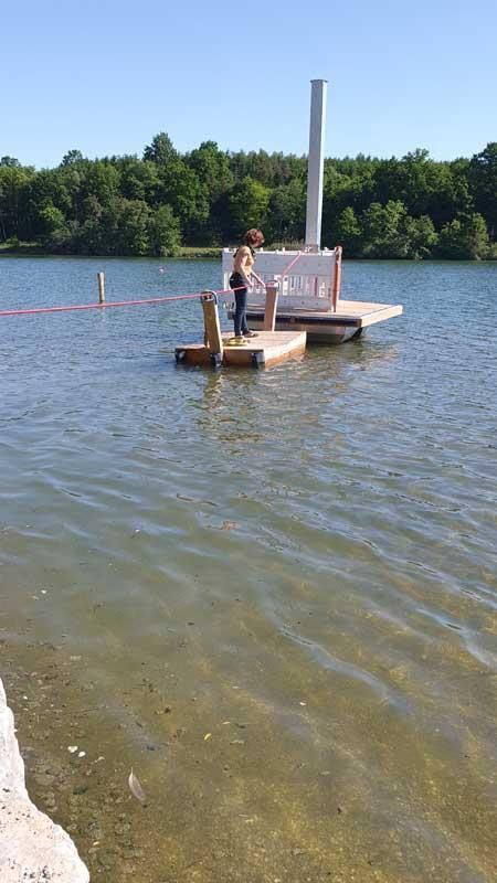 Eine Person steht auf einem Steg mitten auf einem See.