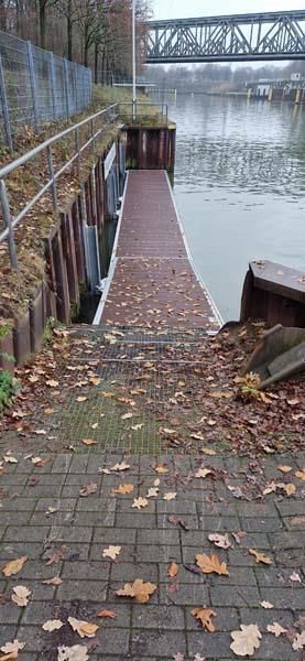 Ein Dock, das zu einem Gewässer führt, mit einer Brücke im Hintergrund.