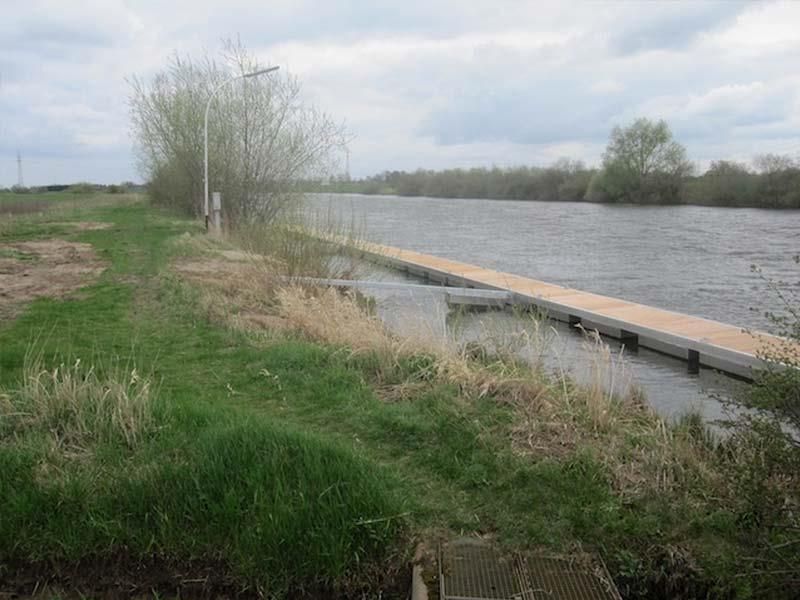 Am Ufer eines Flusses liegt ein Holzsteg.